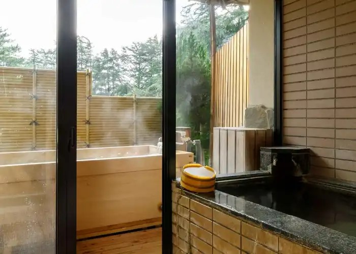 The private Hinoki cypress bathtub at Matsusaki Ryokan, filled with steaming hot spring water.
